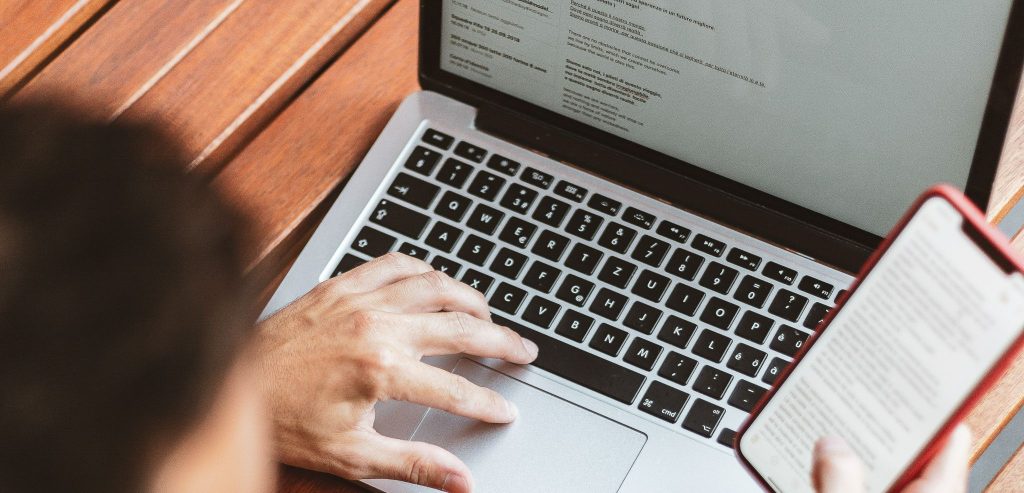 Cybersecurity - man typing and holding a phone