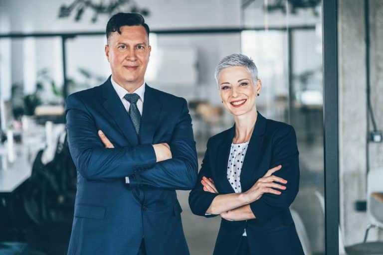 Businessman and businesswoman standing confidently with arms crossed