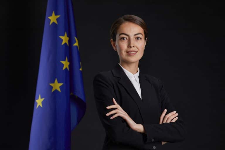 Young female executive smiling with arms crossed in front of EU flag