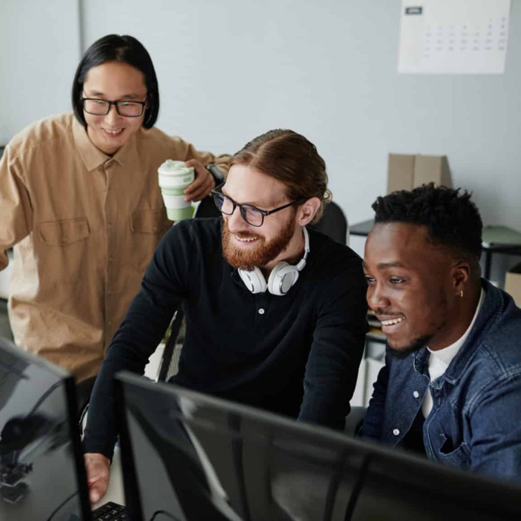Three colleagues collaborating at a computer screen in an office