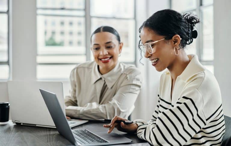 Businesswomen working on a laptop with happy team in office