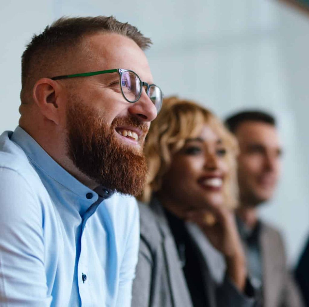 lose-up of three smiling colleagues’ faces with two in the background blurred