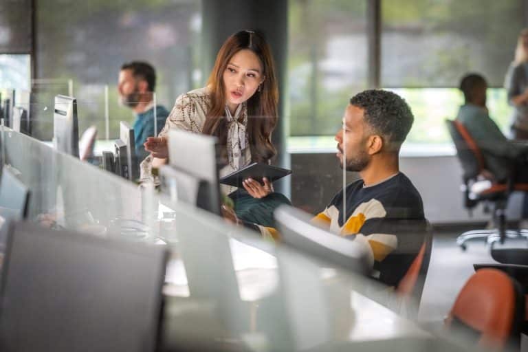Man and woman discussing over a digital tablet in a modern office