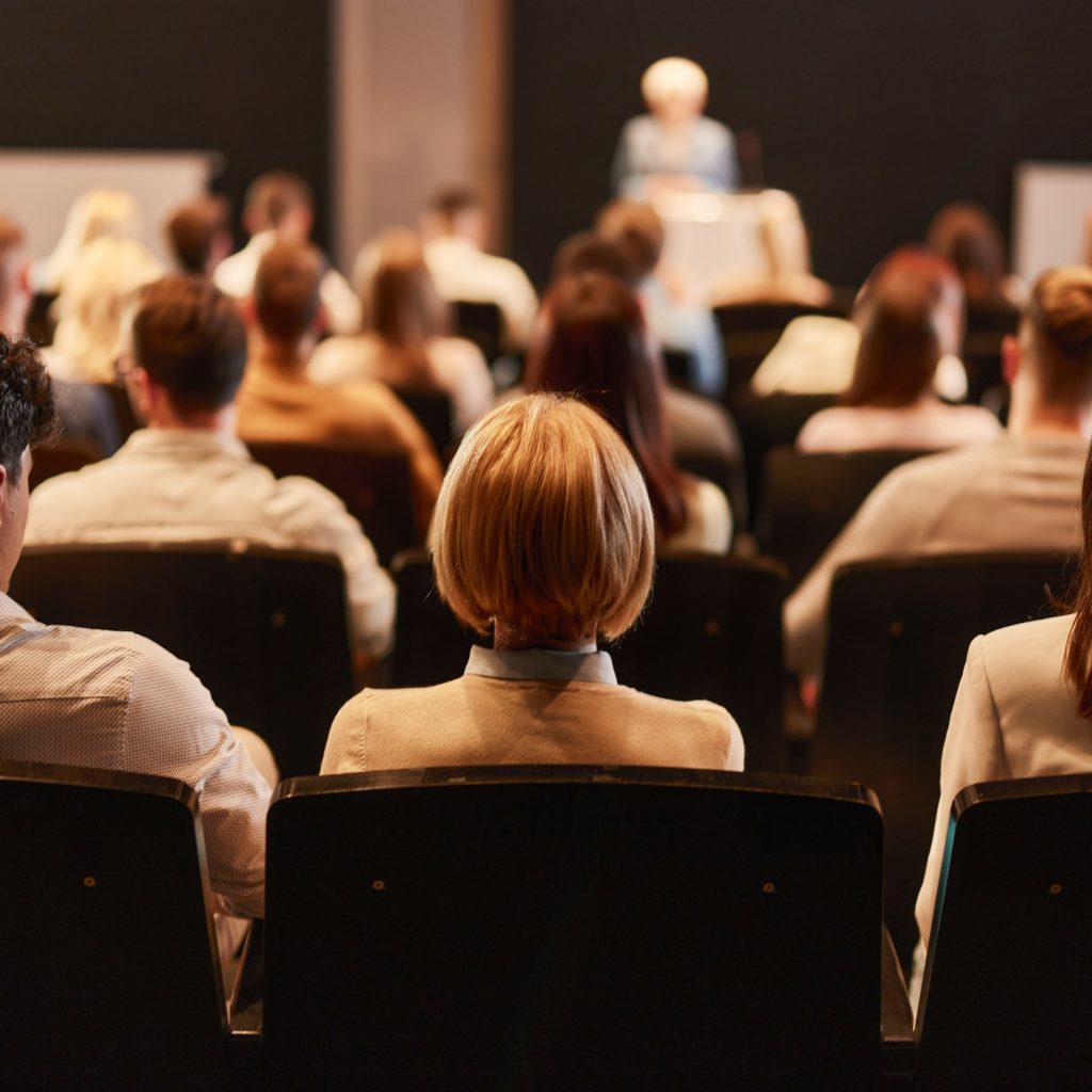 Rear view of audience attending a press conference in a convention center