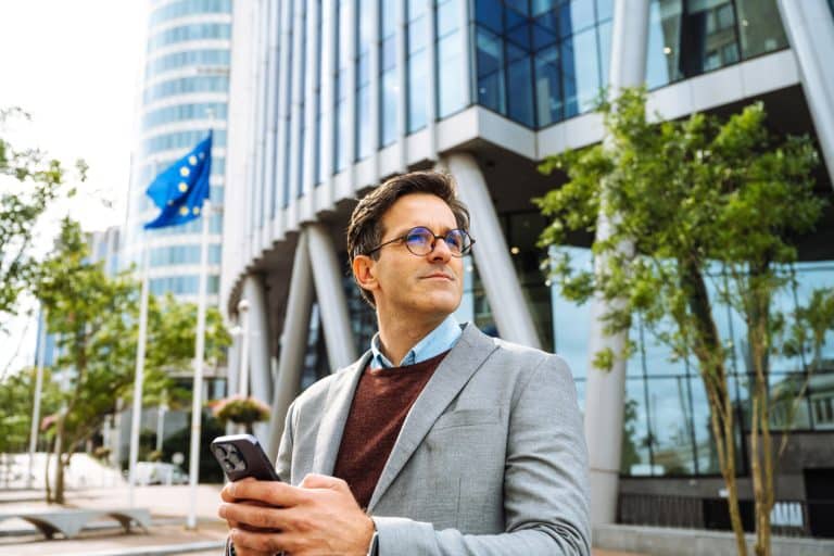 business professional standing in front of building on phone.